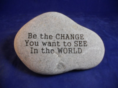 engraved rock and slate signs that says be the change you want to see in the world