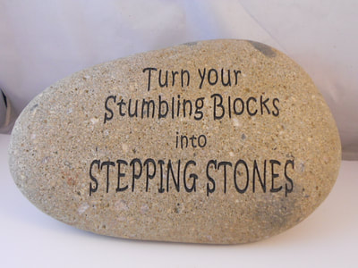 engraved funny rock sign that says, turn your stumbling blocks into stepping stones